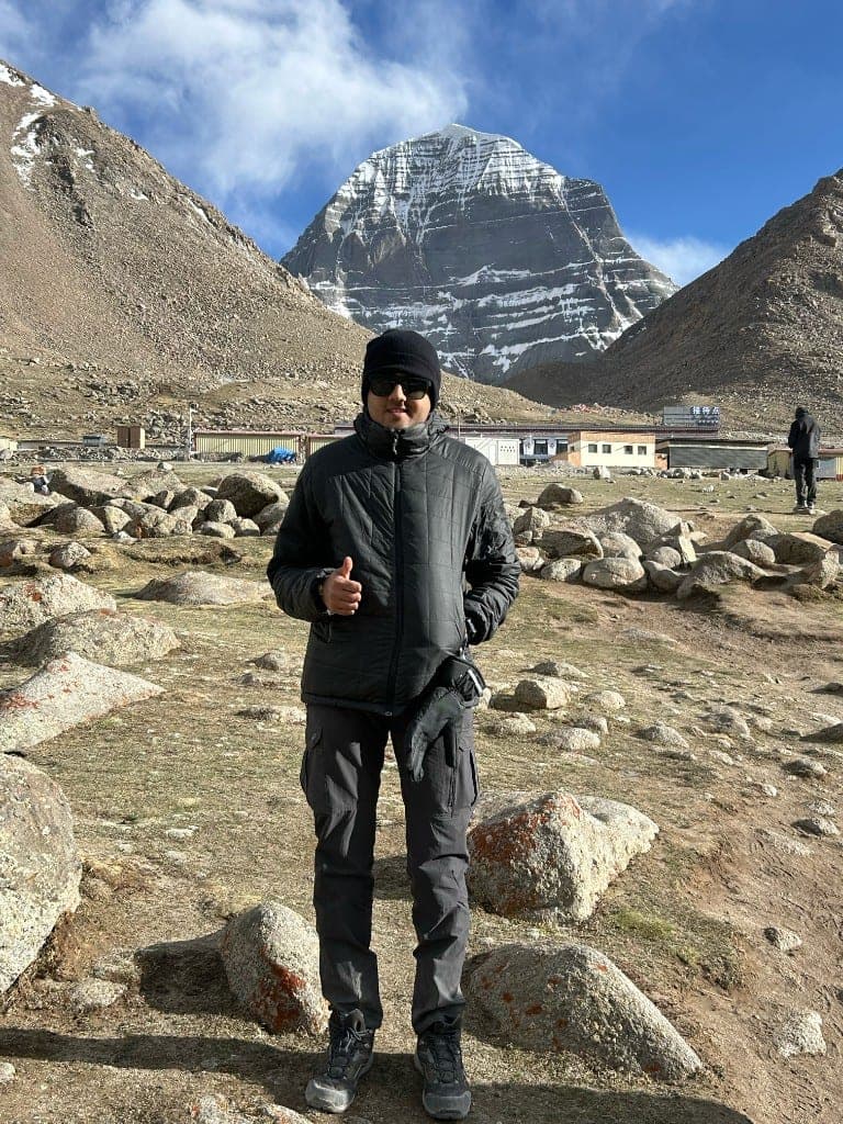 Jalaj at Mount Kailash giving a thumbs up in front of the sacred mountain