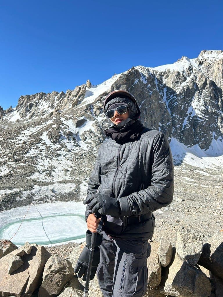 Jalaj trekking in the mountains with snow-covered peaks behind him