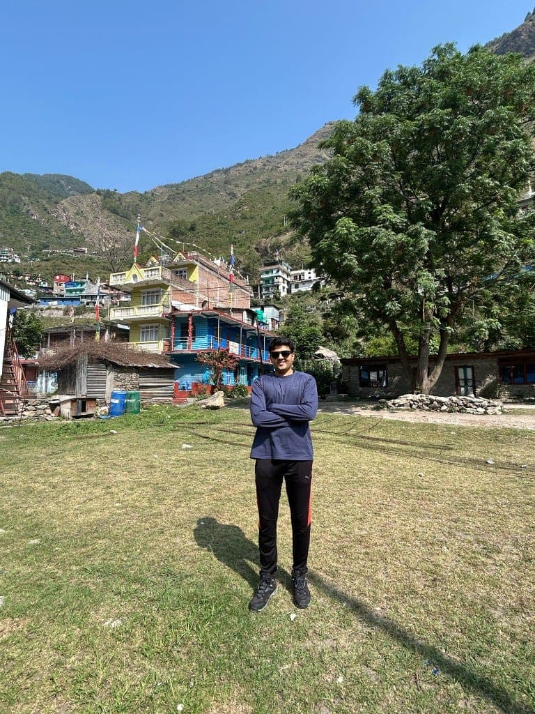 Jalaj standing in a mountain village on a sunny day